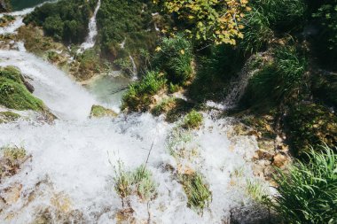 Plitvice Gölleri 'ndeki güzel şelalelerin manzarası. Mavi suyu olan göllerin etrafındaki kayalar ve yeşil ağaçlar. Hırvatistan 'daki Plitvice Gölleri Ulusal Parkı nefes kesici bir manzara.