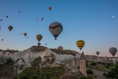 Sıcak hava balonları Kapadokya 'daki tuhaf kaya manzarasının üzerinde uçuyor. Balonlar sabah erkenden uçar. Sabah gökyüzünde güzel sıcak hava balonları. Gökyüzünde ay var. Gorme. Türkiye