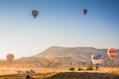 Sıcak hava balonları sabahın erken saatlerinde havalanır. Sıcak hava balonları Kapadokya 'daki tuhaf kaya manzarasının üzerinde uçuyor. Sabah gökyüzünde güzel sıcak hava balonları. Gorme. Türkiye