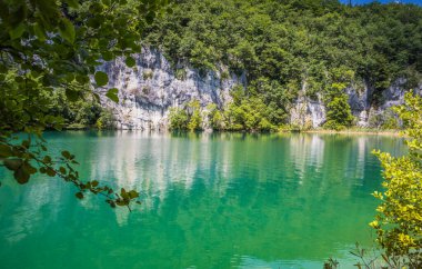 Plitvice Gölleri 'ndeki güzel şelalelerin manzarası. Mavi suyu olan göllerin etrafındaki kayalar ve yeşil ağaçlar. Hırvatistan 'daki Plitvice Gölleri Ulusal Parkı nefes kesici bir manzara.
