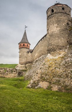 Kamianets-Podilskyi Kalesi 'nin bulutlu bir gökyüzünün altındaki kısmı. Tarihi Kamianets-Podilskyi şehrinin pitoresk doğası arasında yer alan kalenin güçlü kaleleri ve kuleleri,
