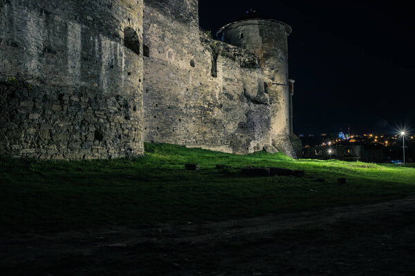 View of the towers and walls of the Kamianets-Podilskyi Castle in the night. Stone bastion of an ancient castle. Beautiful stone castle on the hill at night. Ukraine