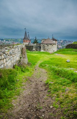 Yaşlı Kamianets-Podilskyi Kalesi bulutlu gri gökyüzünün altında. Kale, Ukrayna 'nın tarihi Kamianets-Podilskyi kentindeki pitoresk doğa arasında yer alıyor.