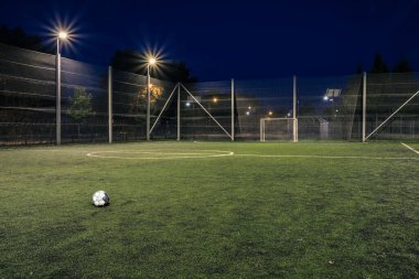 Geceleri top yanan amatör bir futbol sahası. Geceleri fenerlerle aydınlatılan küçük bir futbol sahası. Geceleri yeşil futbol sahası aydınlanıyor. Geceleri spot ışıklarıyla futbol sahası