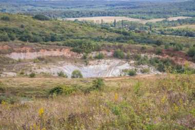 Eski kapalı taş ocağı. Eski bir taş ocağında su birikintisi. Ukrayna 'daki dağlarda eski kapalı bir taş ocağının içinde fıtık orogeninin jeolojik yapıları üzerinde büyüyen ağaçlar.