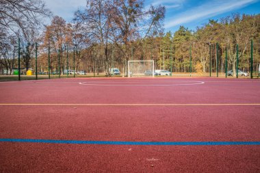 Amatör futbol sahası, güneşli bir yaz gününde, kırmızı bir yüzeyde. Kırmızı yüzeyi olan bir yerleşim bölgesinde futbol sahası