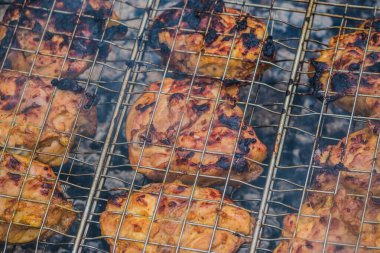 Bir tavuk kızartılıyor, önemli miktarda duman çıkıyor. Bu pişirme işlemi genellikle barbekü ve dışarıda ızgara yapmakla ilişkilendirilir.