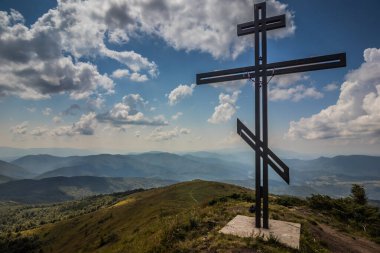 Bir dağ zirvesinde ortodoks geçişi nefes kesici bir panoramik manzara ve bulutlu bir gökyüzü.