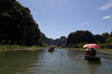 NINH BINH, VİETNAM 4 AUGUSTUS 2024: Turistler Vietnam 'da Ninh Binh' de Tam Coc ve Trang An 'ın muhteşem yeşil doğası ve tebeşir uçurumlarında kürek çekerek seyahat ediyorlar