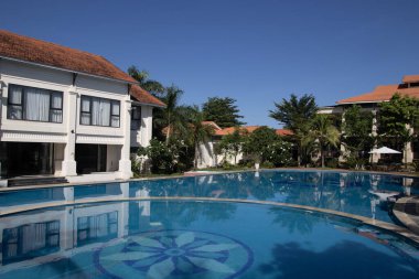 Vietnam 'daki Dong Hoi sahillerinde huzur ve sükuneti seven turistler için havuzlu palmiye ağaçları olan otel.