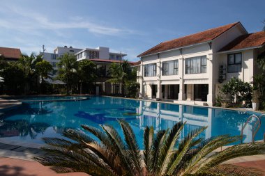 Vietnam 'daki Dong Hoi sahillerinde huzur ve sükuneti seven turistler için havuzlu palmiye ağaçları olan otel.