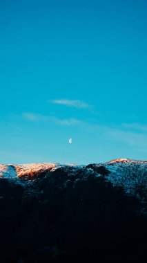 Norveç 'in dağlarındaki Ay manzarası. Karlı dağlar, akşam ve ay