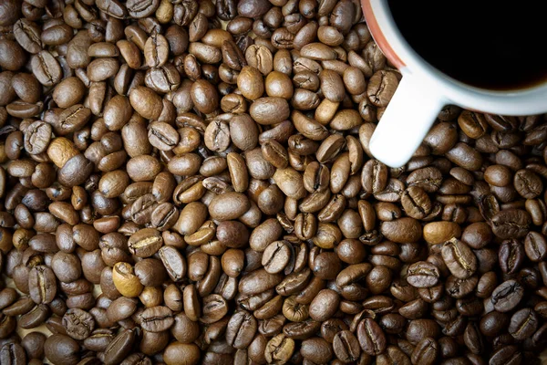 テーブルの上に焙煎したコーヒー豆とコーヒーカップ — ストック写真