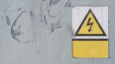   Endüstriyel bir binanın kapısında yüksek voltaj göstergesi olan eski tehlike işareti.                             