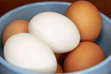   Mutfak masasındaki kasede taze kahverengi ve beyaz yumurtalar.                              