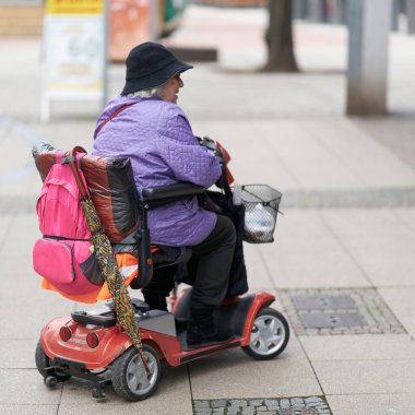 Magdeburg, Germany  January 14, 2023: elderly woman with electric scooter doing window shopping in downtown Magdeburg, Germany                                