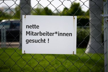 Sign in front of a company premises in Germany with the inscription nette Mitarbeiter und Mitarbeiterinnen gesucht. Translation: nice male and female employees wanted                               
