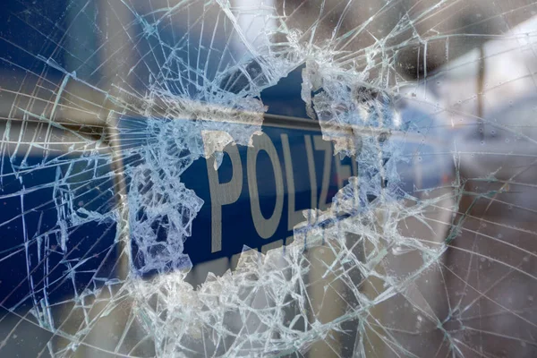 Broken glass and a police car as a symbol of violence against the police