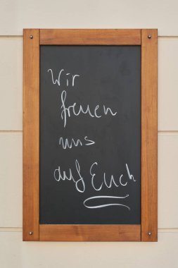   Berlin 'de bir restoranın önünde Almanca yazan Wir freuen uns auf euch ile imza atın. Tercümesi: Sizi dört gözle bekliyoruz.                             