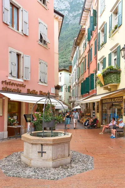   Riva del Garda, İtalya 3 Ağustos 2023: İtalya 'nın Garda Gölü' ndeki eski Riva del Garda kasabası, turistler arasında popüler, mağazalar ve ön planda bir çeşme                             