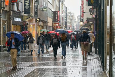   Köln, Almanya 24 Mayıs 2024: Yağmurlu havalarda Köln 'de popüler bir alışveriş caddesindeki insanlar                             