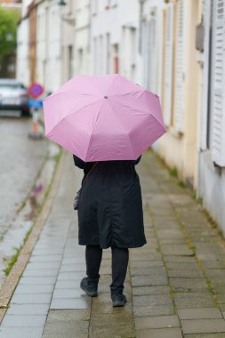  Belçika 'nın eski Bruges kasabasında yağmurlu havada şemsiyeli bir kadın.                              