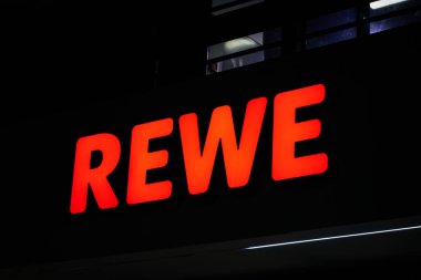 Berlin, Almanya 30 Mart 2024: Alman gıda perakendecisi Rewe 'nin Berlin' deki bir Rewe süpermarketindeki aydınlatılmış reklamı                               