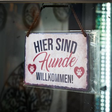 Almanya 'da bir köpek modası mağazasında Alman yazıt hier sind Hunde willkommen ile anlaşma imzalayın. Çevirisi: Burada köpeklere yer var.                               