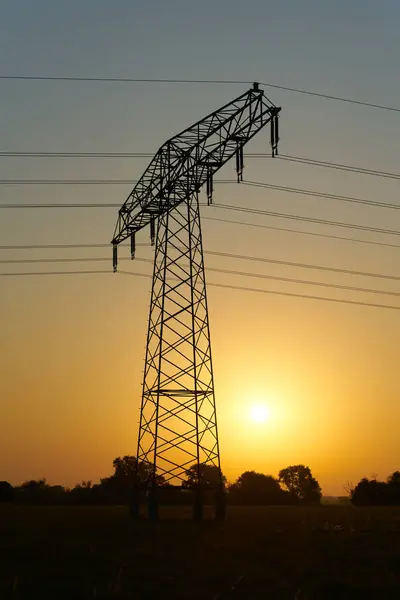 Stock image  Atmospheric sunrise on a field with a power pole in the early morning in Magdeburg in Germany                              