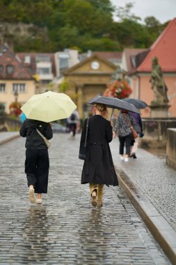 Wuerzburg, Almanya 26 Eylül 2024: Eski Ana Köprü 'de şemsiyeli iki genç kadın, Wurzburg' da yağmur altında Alte Mainbrcke                               