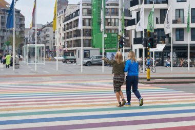 Blankenberge, Belçika 13 Mayıs 2024: Kuzey Denizi 'ndeki Belçika kıyı kenti Blankenberge' de yoldan geçenlerle gökkuşağı renklerinde yaya geçidi                               