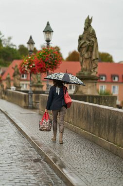   Wurzburg, Almanya 26 Eylül 2024: Wurzburg 'daki eski Ana Köprü' de şemsiyeli kadın                             