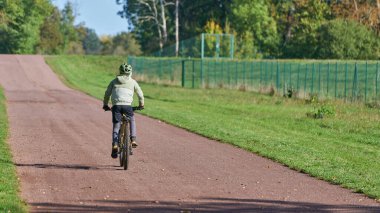 Magdeburg, Almanya 11 Ekim 2024: Magdeburg 'daki Herrenkrugpark yolunda genç bir bisikletçi                               