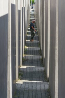   Berlin, Almanya 01 Mayıs 2025: Berlin şehir merkezindeki Yahudi Soykırımı Anıtı 'nın beton blokları arasındaki ziyaretçi                             