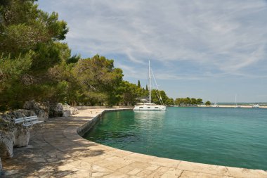   Veliki Brijun Adası, Hırvatistan - Haziran 04, 2025: Hırvatistan kıyısındaki Veliki Brijun adasının kıyı geçidi bir yelkenli tekneyle                             