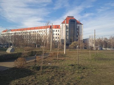 Bulutlu mavi gökyüzünün arka planında kırmızı çatılı bir bina.