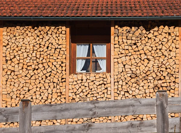 把木柴堆在农家窗前 房顶上有弹壳和木栅栏 — 图库照片
