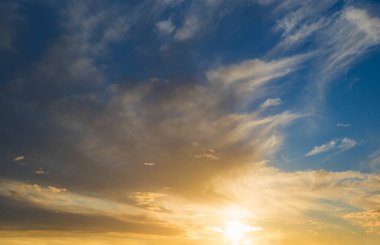sunset scenery blue sky and yellow shiny sinking sun. feathery clouds above