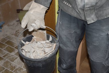 renovation the guest toilet at home. man holding bucket with dameged scraped off tiles