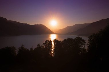 colorful alpine sunset scenery, view to lake Thunersee and sinking sun over tourist resort Interlaken, switzerland. 