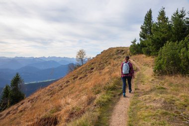 young woman hiking at mountain ridgeway Brauneck, Bavarian alps in autumnal landscape