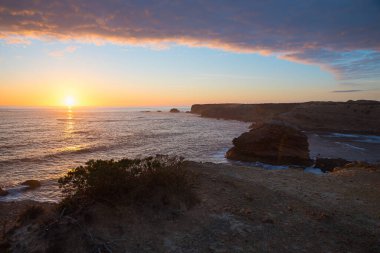 Renkli bulutlar ve batan güneşle Algarve sahilindeki rüya gibi gün batımı manzarası. Kıyı manzarası Carrapateira Portekiz