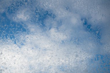 Buzlu kar taneleri ve bulutlu mavi gökyüzü olan bir çatı penceresi. kış arkaplanı