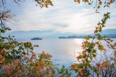 Traunsee Gölü, yapraklarla çerçevelenmiş, yolcu gemisi gezintisi. Arka taraftaki sıradağlarda. manzara Salzkammergut Avusturalya