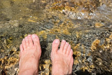 Yaşlı bir kadının ayakları, soğuk bir dağ deresinde sertleşti, Kneipp tedavisi