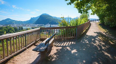 viewpoint with bench and wooden fence, hiking trail Monchsberg mountain, landscape tourist resort Salzburg, austria clipart