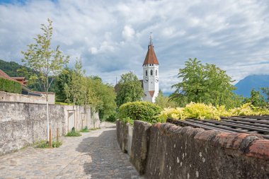 Kale duvarı boyunca yürüme Thun, tarihi şehir kilisesi, yeşil çalılar ve ağaçlar. Tarihi varış yeri Bernese Oberland, İsviçre