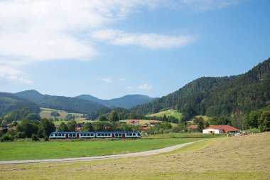 Bavyera Schliersee bölgesinden geçen tren. Alpler manzaralı kırsal alan ve biçilmiş tarlalar