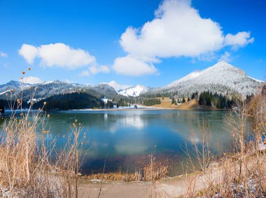 view from the parking area above to lake Spitzingsee, snow covered Brecherspitze mountain, bavarian alps in winter. blue sky with clouds clipart