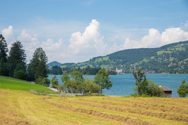 Schliersee yaz manzarası, göl kıyısı Fischhausen, biçilmiş tarla. Karşı taraftaki kiliseye bak..